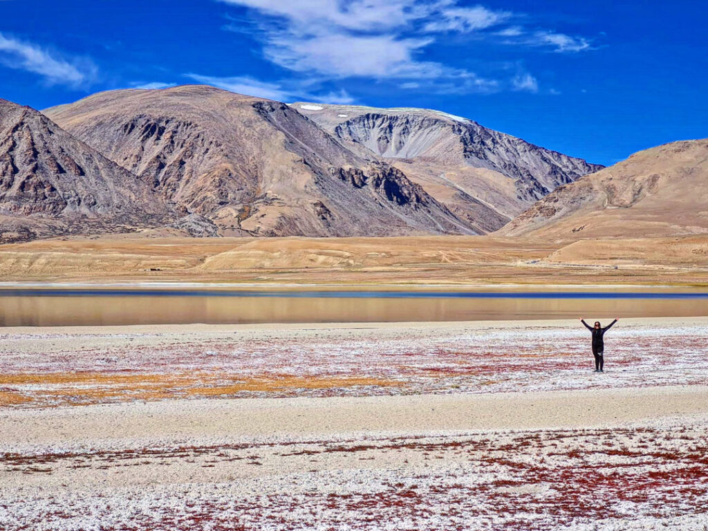Paesaggio montano del Ladakh con una persona a braccia aperte tra le montagne dell'Himalaya indiana