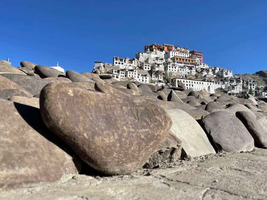 Monastero buddhista del Ladakh su una collina con pietre incise in primo piano