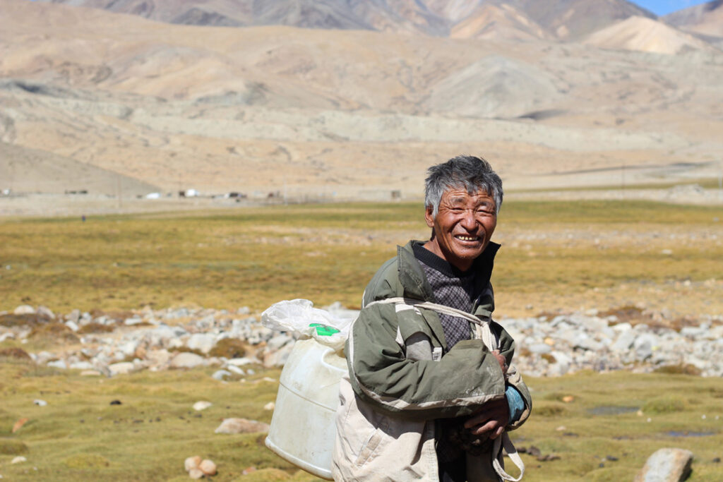 Uomo sorridente fotografato in un paesaggio montano durante un viaggio in Ladakh