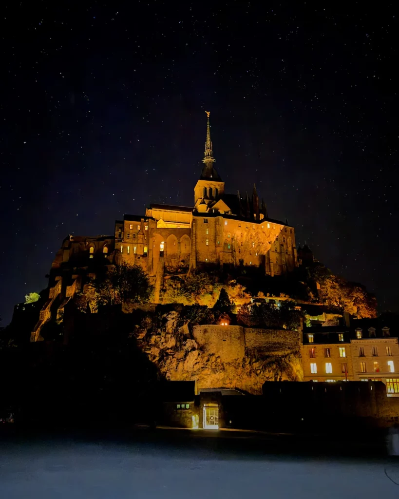 Mont Saint-Michel illuminato di notte con l'abbazia in cima al borgo