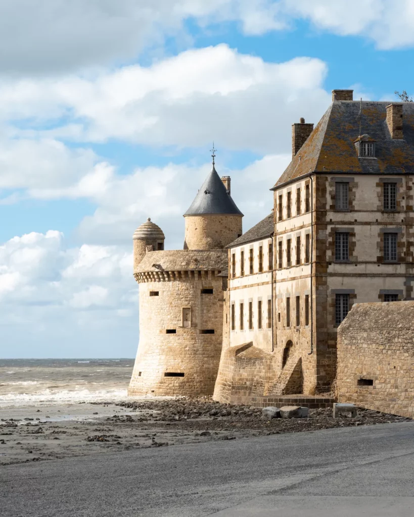Mura e torre del borgo di Mont Saint-Michel con la baia sullo sfondo